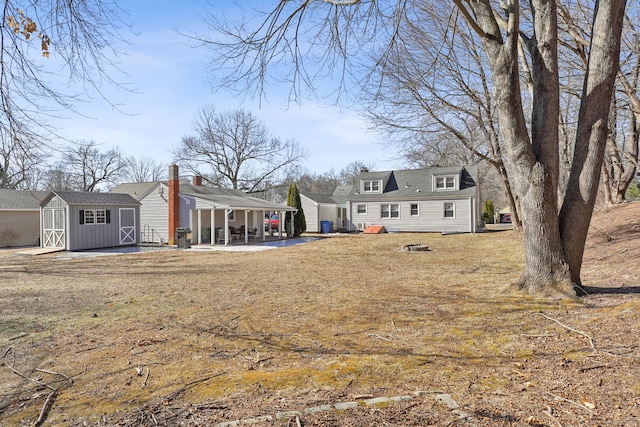 back of house featuring a storage shed, a patio, and an outdoor structure