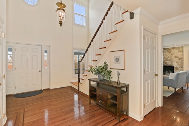 foyer entrance with crown molding, plenty of natural light, stairway, and wood finished floors