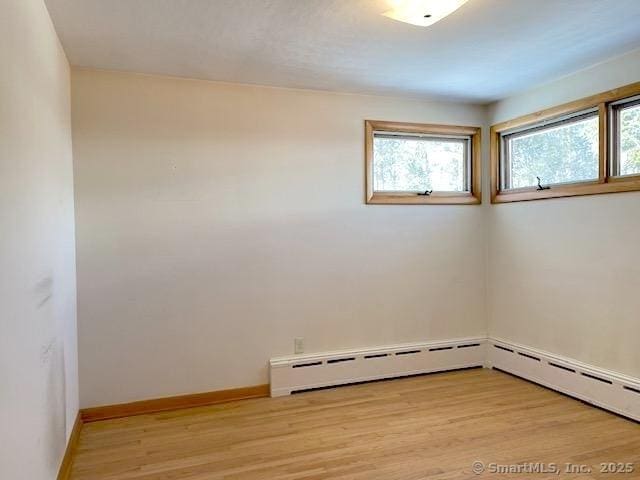 empty room with a baseboard heating unit and light hardwood / wood-style floors