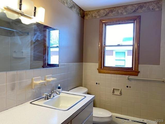 bathroom featuring vanity, a wealth of natural light, tile walls, and toilet