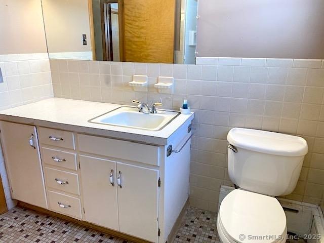 bathroom with vanity, tile patterned flooring, tile walls, and toilet