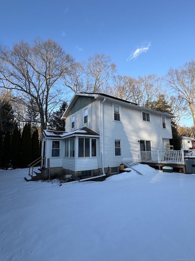 snow covered property featuring central AC, a sunroom, and a deck