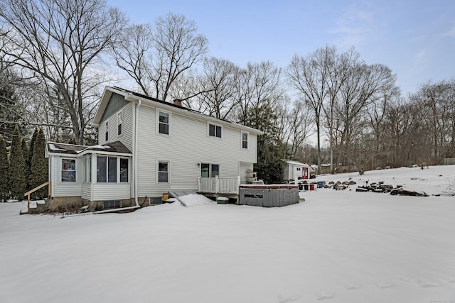 snow covered rear of property with a sunroom and a deck