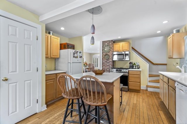 kitchen with sink, decorative light fixtures, a center island, light hardwood / wood-style flooring, and appliances with stainless steel finishes