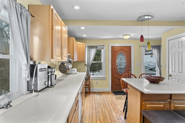 kitchen featuring sink, a breakfast bar area, hanging light fixtures, a kitchen island, and light wood-type flooring