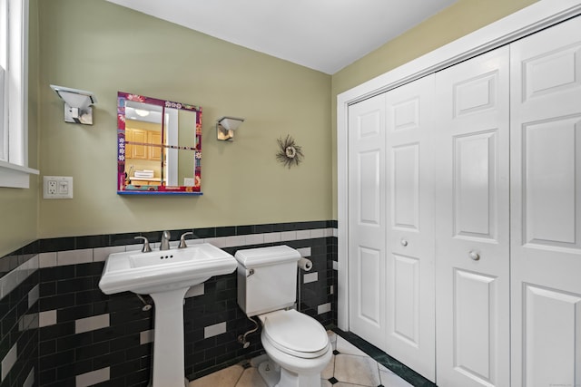 bathroom with tile patterned floors, toilet, and tile walls