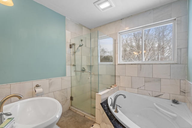 bathroom with shower with separate bathtub, sink, and tile walls