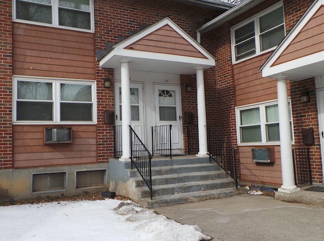 snow covered property entrance featuring brick siding