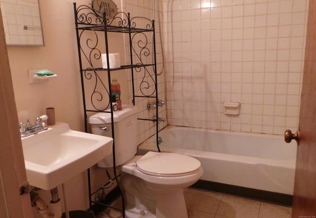 bathroom featuring shower / washtub combination, a sink, toilet, and tile patterned floors