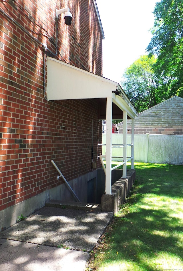 view of home's exterior with brick siding, a lawn, and fence