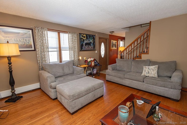 living room featuring baseboard heating, light hardwood / wood-style floors, and a textured ceiling