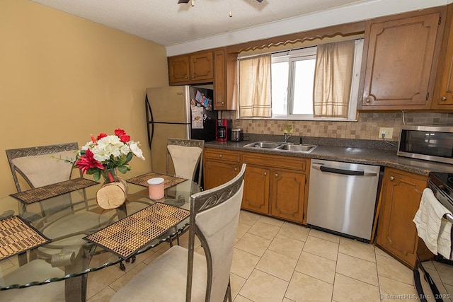 kitchen featuring appliances with stainless steel finishes, sink, light tile patterned floors, and decorative backsplash