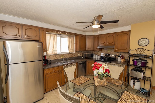 kitchen featuring appliances with stainless steel finishes, sink, backsplash, light tile patterned floors, and ceiling fan