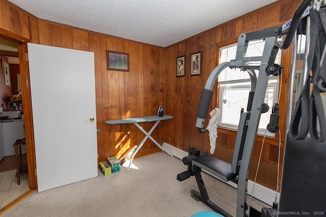 exercise area with light colored carpet, a textured ceiling, and wood walls