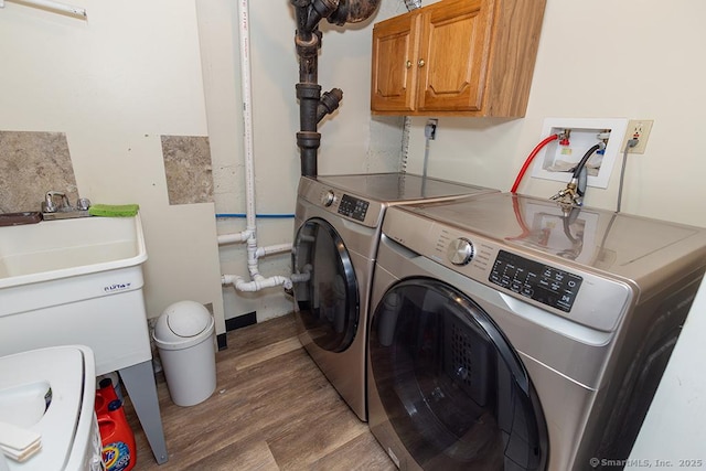 clothes washing area with cabinets, wood-type flooring, and independent washer and dryer