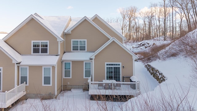 snow covered house with a wooden deck