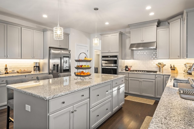 kitchen featuring pendant lighting, gray cabinets, stainless steel appliances, and a kitchen breakfast bar