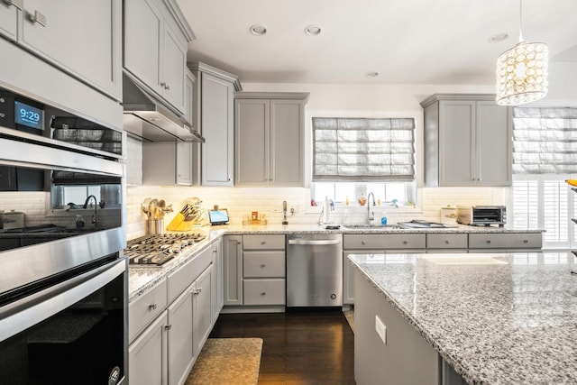 kitchen featuring stainless steel appliances, sink, gray cabinetry, and decorative light fixtures