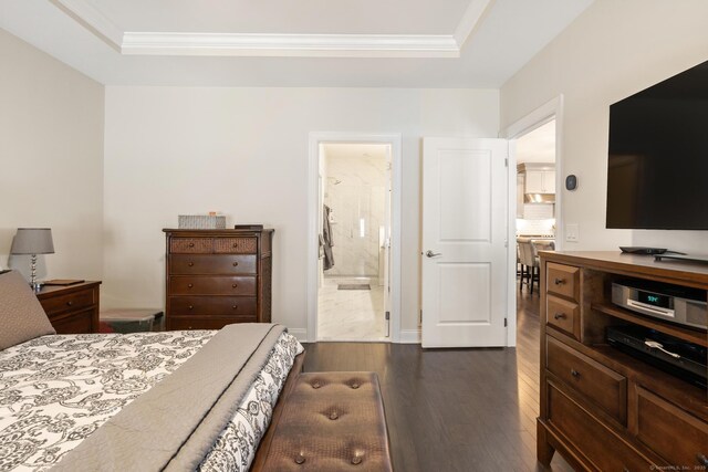 bedroom featuring dark wood-type flooring, ornamental molding, connected bathroom, and a raised ceiling