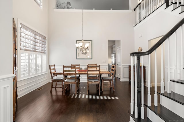 dining space with dark hardwood / wood-style flooring, a notable chandelier, and a high ceiling