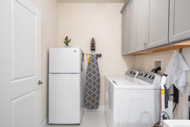 laundry area with light tile patterned floors, washing machine and dryer, and cabinets