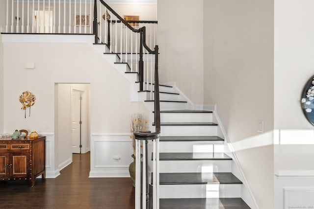 stairs featuring wood-type flooring and a high ceiling