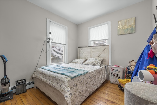 bedroom with a baseboard radiator and light hardwood / wood-style flooring