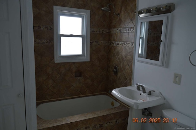 bathroom featuring tiled shower / bath and toilet