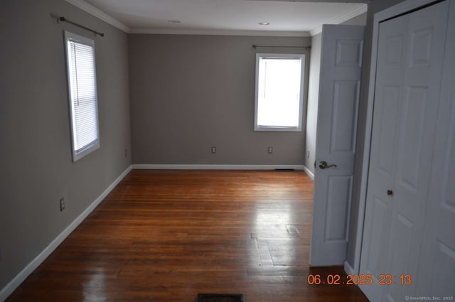 unfurnished bedroom with crown molding, a closet, dark hardwood / wood-style floors, and multiple windows