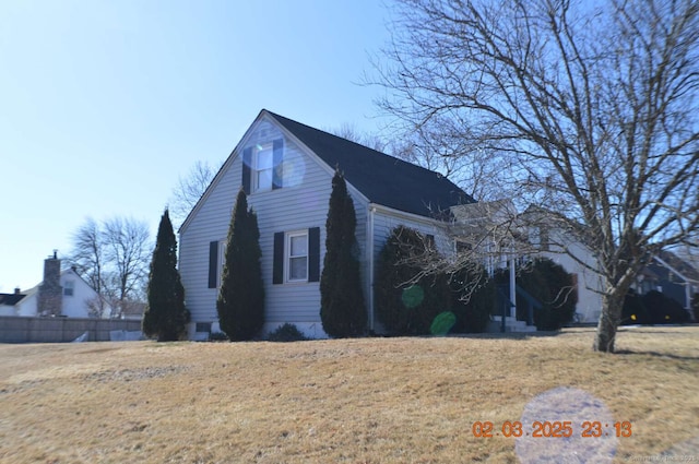 view of side of home with a lawn and fence