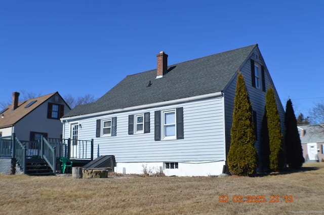 back of house featuring roof with shingles, a yard, a chimney, and a wooden deck