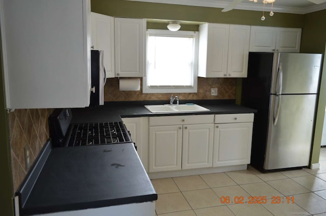 kitchen with freestanding refrigerator, a sink, white cabinetry, backsplash, and gas stove