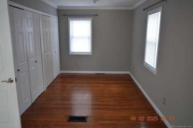 unfurnished bedroom with baseboards, visible vents, wood finished floors, and ornamental molding