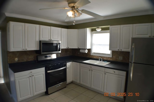 kitchen featuring dark countertops, white cabinets, stainless steel appliances, and a sink