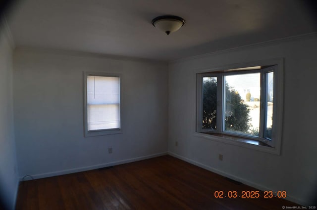 spare room with ornamental molding, visible vents, baseboards, and wood finished floors