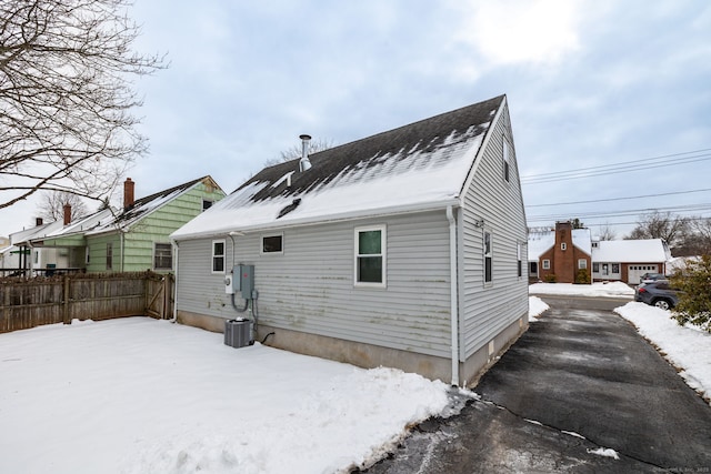 snow covered back of property with central AC unit