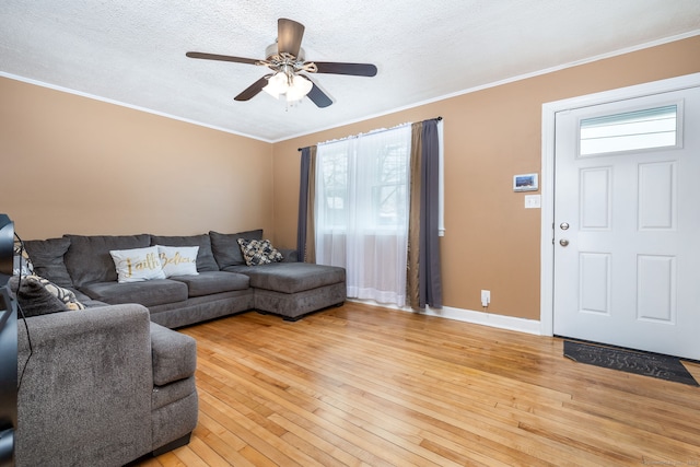 living room featuring ornamental molding, a textured ceiling, and light wood-type flooring