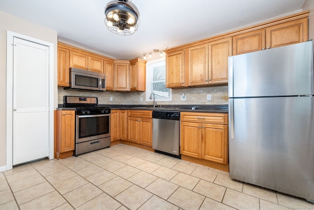 kitchen featuring light tile patterned flooring, appliances with stainless steel finishes, sink, and backsplash