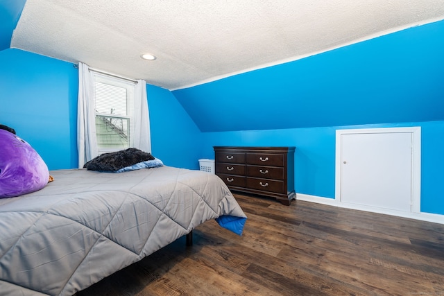 bedroom featuring dark hardwood / wood-style flooring, vaulted ceiling, and a textured ceiling