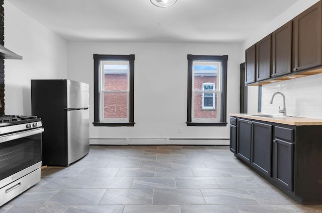 kitchen with sink, tasteful backsplash, dark brown cabinets, appliances with stainless steel finishes, and a baseboard heating unit