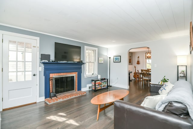 living room featuring a brick fireplace, crown molding, and dark hardwood / wood-style flooring