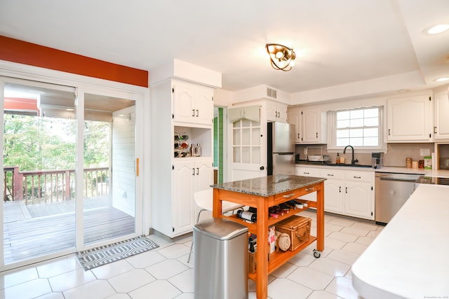 kitchen with light tile patterned floors, sink, backsplash, white cabinetry, and stainless steel appliances