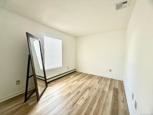 empty room featuring a baseboard heating unit and light wood-type flooring