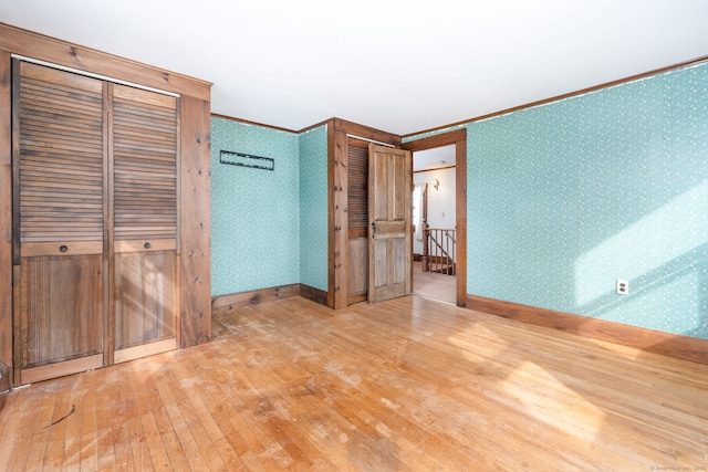 unfurnished bedroom featuring hardwood / wood-style flooring, ornamental molding, and multiple closets