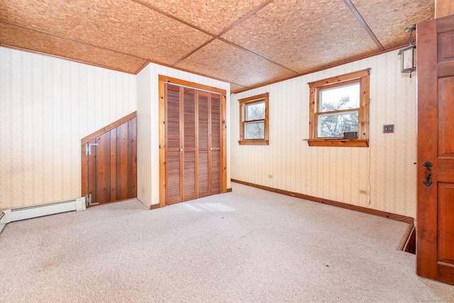 unfurnished bedroom featuring a baseboard heating unit, ornamental molding, and carpet flooring