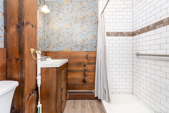 bathroom with hardwood / wood-style floors, a baseboard heating unit, vanity, toilet, and walk in shower