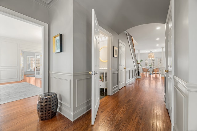 corridor with arched walkways, a healthy amount of sunlight, and a decorative wall