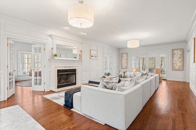 living room featuring crown molding, dark wood-style floors, a high end fireplace, and a decorative wall