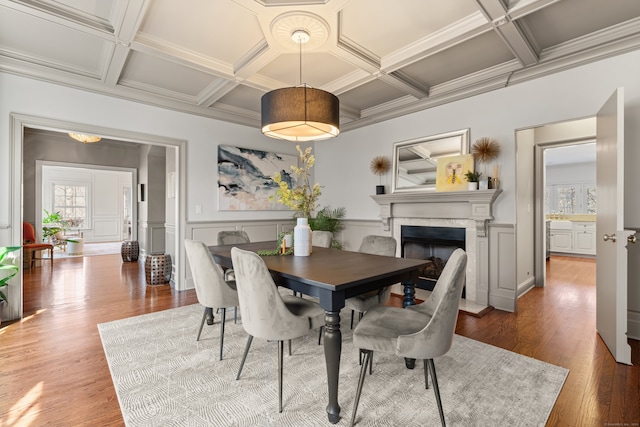 dining space with coffered ceiling, wainscoting, wood finished floors, beam ceiling, and a high end fireplace