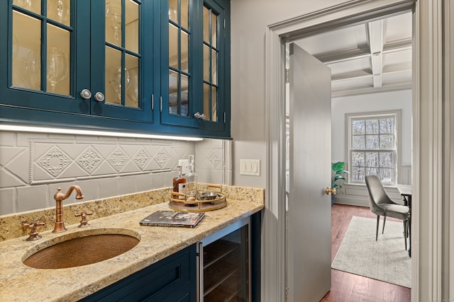 kitchen with coffered ceiling, wine cooler, glass insert cabinets, blue cabinets, and a sink